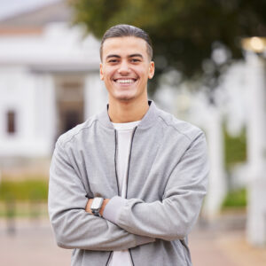 Education, smile and college with portrait of man on campus with arms crossed for learning, scholar.